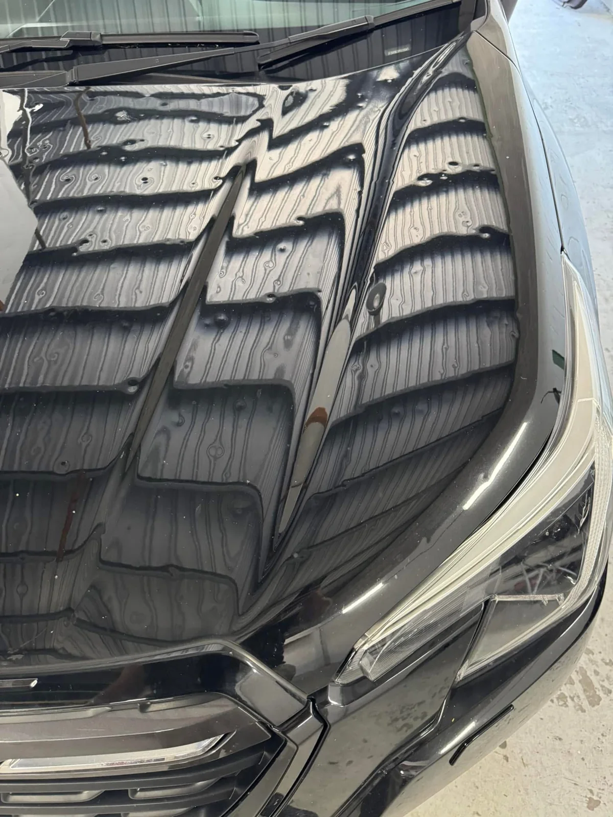 Before repair: dark Subaru bonnet right view showing hail dents