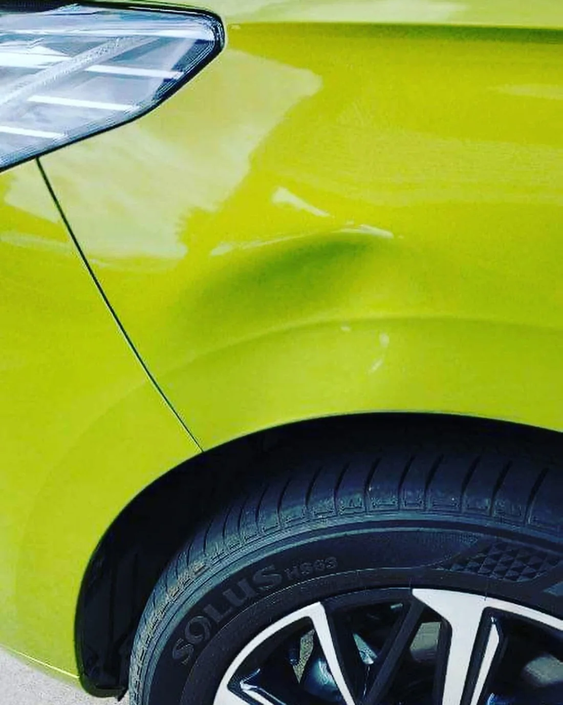 Before: dent above the front wheel on a lime green Haval