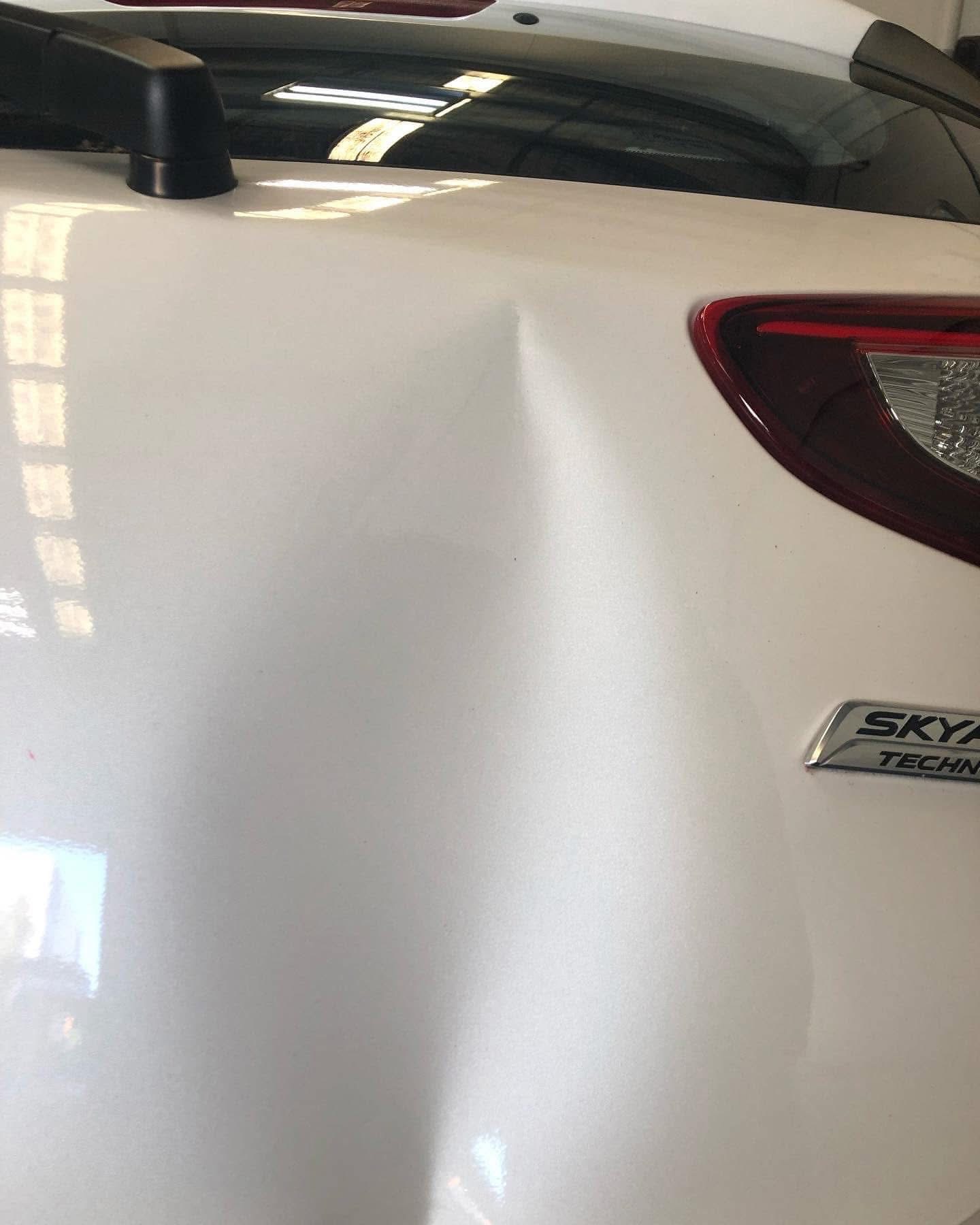 Before repair: close view of damage on the white Mazda hatch near the right tail light